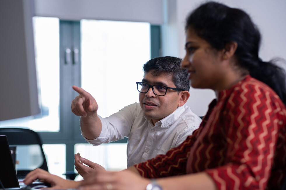 Two people sitting in front of a computer in the Dukosi office