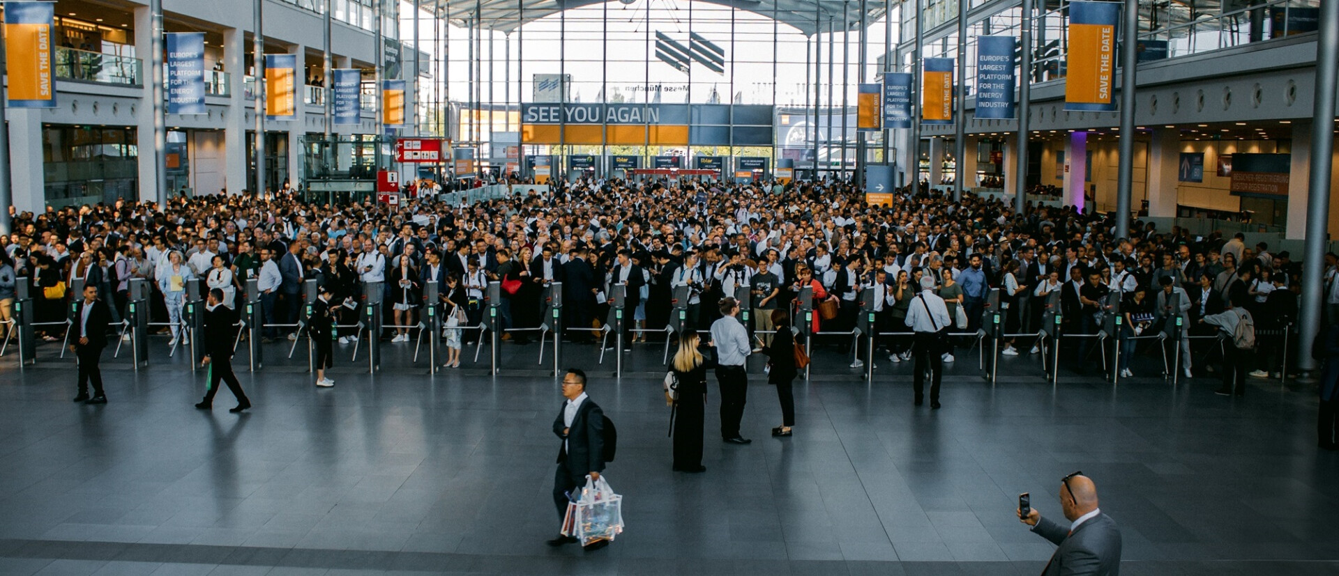 A large group of people queueing for an event inside a large open space building