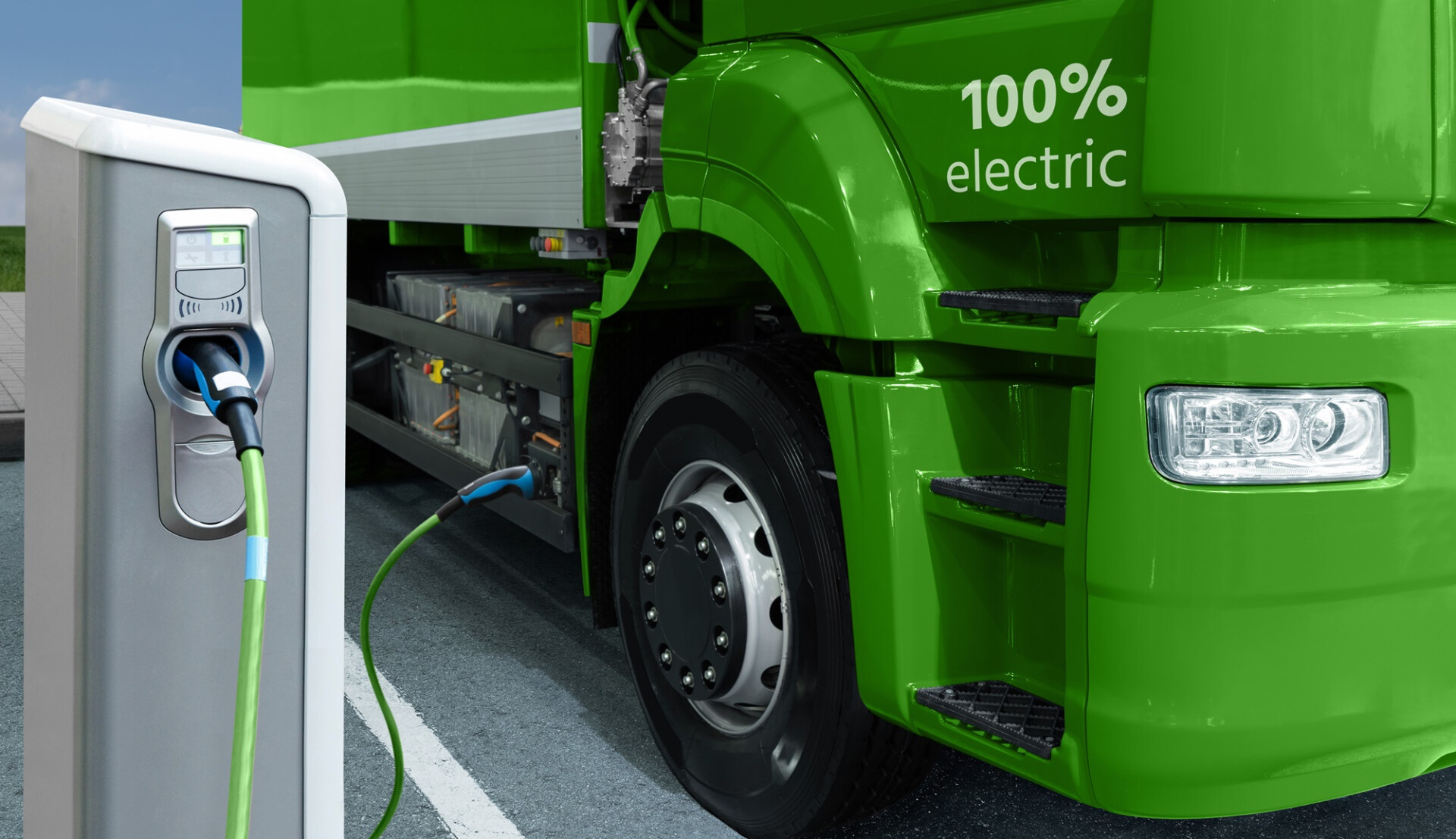 a green truck with an electric charger plugged into it